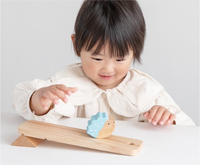 ２歳くらいの女の子が、retron forestのとことこスロープトイ『あわてんぼうハリー』をスロープで転がしている様子。